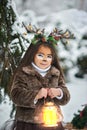 Fairy tale girl. Portrait a little girl in a deer dress with a painted face in the winter forest. Big brown antler