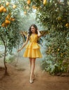 fairy tale girl walking in fabulous lemon garden. Fantasy woman in short yellow dress pixie costume, fake plastic Royalty Free Stock Photo