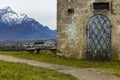 Fairy tale gorgeous highland medieval knight castle stone exterior iron door on plateau space with picturesque Alps mountains