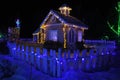 Fairy-tale house in the lights and a luminous window with a Christmas tree . Night photo. Royalty Free Stock Photo