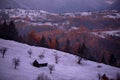 Fairy tale landscape with a rocky mountain full of snow at sunset. A village of traditional Romanian old houses over a valley. Royalty Free Stock Photo