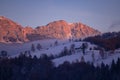 Fairy tale landscape with a rocky mountain full of snow at sunset. A village of traditional Romanian old houses over a valley. Royalty Free Stock Photo