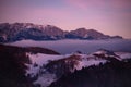 Fairy tale landscape with a rocky mountain full of snow at sunset. A village of traditional Romanian old houses over a valley. Royalty Free Stock Photo