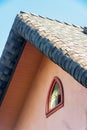 Fairy tale style roof with round edge and gray tiles with beige or red stucco exterior and small tear drop window