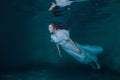 Fairy woman in white dress underwater.