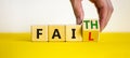 Faith instead fail symbol. Businessman turns a wooden cube and changes the word fail to faith. Beautiful yellow table, white Royalty Free Stock Photo