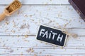 Faith handwritten text word with chalk, spoon with mustard seeds, and closed holy Bible book on wooden background