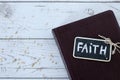 Faith handwritten word with chalk, spilled mustard seeds, and closed holy bible book on wooden background