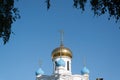 Faith and religious architecture concept. Exterior Christian church with golden domes and crosses against blue sky framed by trees