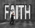 Faith word on concrete wall with man holding hammer