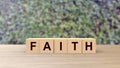 Faith word wooden cubes on table vertical over blur background with climbing green leaves, mock up, Christianity and Catholicism, Royalty Free Stock Photo