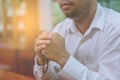 A faithful Asian young male hands in prayer gesture sitting alone on sofa at church pray and hope for good luck, success, forgiven