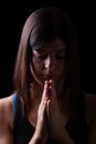 Faithful athletic woman praying, with hands folded in worship to god, head down and eyes closed Royalty Free Stock Photo