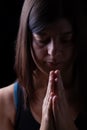 Faithful athletic woman praying, with hands folded in worship to god