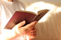 Faithful Christian woman holding gold Holy Bible. Early morning prayer to God and Jesus Christ Royalty Free Stock Photo