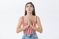 Faithful adult woman in striped top and headband holding palms in pray against chest raising head up looking in sky