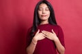 Faithful woman closes eyes and keeps hands on chest near heart, shows her kindness Royalty Free Stock Photo