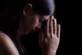 Faithful woman praying, with hands folded in worship touching the forehead