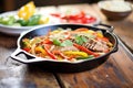 fajitas sizzling in cast iron pan, peppers, onions