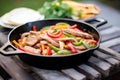 fajitas sizzling in cast iron pan, peppers, onions