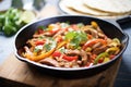 fajitas with sizzling peppers and onions on a castiron pan Royalty Free Stock Photo