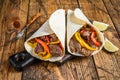 Fajitas Tortilla wrap with beef meat stripes, colored bell pepper and onions and salsa. Wooden background. Top view