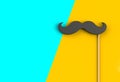 Fake black mustache on yellow and blue background. Royalty Free Stock Photo