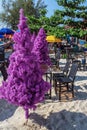 Fake christmas tree on tropical beach with chairs and tables around