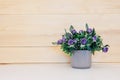 Fake flower in vase on wood background.