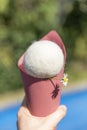 A fake ice cream is built with a red cardboard cone and a white wool ball on a green and blue background, with a decorative daisy Royalty Free Stock Photo