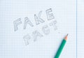 Fake news concept. Fake - Fact. Drawing in a notebook and pencil. Erased word fact. Fake information concept. Top view