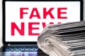 Fake news. Newspapers and laptop. Pile of daily papers with news on the laptop Royalty Free Stock Photo