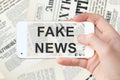 Fake news written on a computer smartphone screen, newspapers background Royalty Free Stock Photo