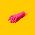Fake pink hand on yellow background. Fashion still life isometric art