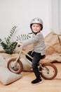 Fake-smiling blond boy posing for a photo on a small beige two wheel bike Royalty Free Stock Photo