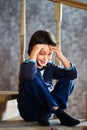 Fake tears of little boy, 7 years old, of European appearance, sitting on step of wooden staircase in private two story Royalty Free Stock Photo