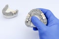 fake teeth. metal and ceramic crowns and bridges. the dentist`s hand holds a plaster model