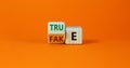 Fake or true symbol. Turned a wooden cube and changed the word `fake` to `true` or vice versa. Beautiful orange table, orange Royalty Free Stock Photo