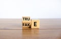 Fake or true symbol. Turned a wooden cube and changed the word `fake` to `true` or vice versa. Beautiful wooden table, white Royalty Free Stock Photo