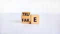 Fake or true symbol. Turned a wooden cube and changed the word `fake` to `true` or vice versa. Beautiful white table, white Royalty Free Stock Photo