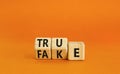 Fake or true symbol. Turned wooden cubes and changed the word fake to true or vice versa. Beautiful orange table, orange Royalty Free Stock Photo