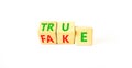 Fake or true symbol. Turned wooden cubes and changed the word fake to true or vice versa. Beautiful white table, white background Royalty Free Stock Photo