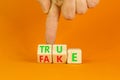 Fake or true symbol. Turned wooden cubes and changed the word fake to true or vice versa. Beautiful orange table, orange Royalty Free Stock Photo