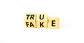 Fake or true symbol. Turned wooden cubes and changed the word fake to true or vice versa. Beautiful white table, white background Royalty Free Stock Photo