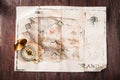 Fake vintage old broken map on wooden desk with compass. Pirates treasure map Royalty Free Stock Photo