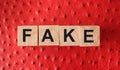 FAKE word written in wooden blocks on red leather. Fake or real news, myth or true concept Royalty Free Stock Photo