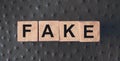 FAKE word written in wooden blocks on red leather. Fake or real news, myth or true concept Royalty Free Stock Photo