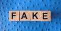 FAKE word written in wooden blocks on red leather. Fake or real news, myth or true concept