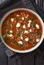 Fakes Greek lentil soup served with feta close-up in a plate. Vertical top view