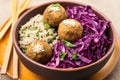 a falafel bowl with brown rice and purple cabbage served in a bamboo bowl